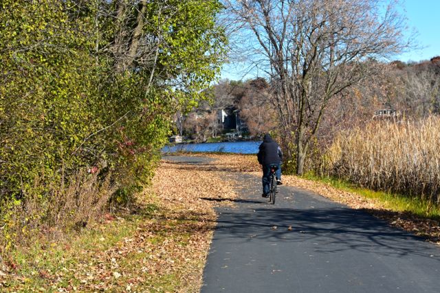 biker on a paved trail next to a lake