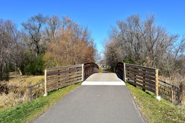 a small bridge along a paved bike trail in french regional park