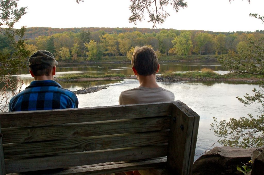 two boys sitting on a bench above the St Croix river