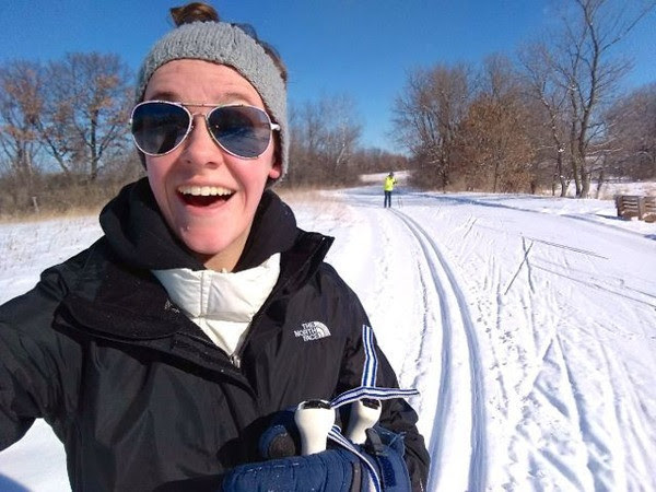 woman cross country skiing with a big smile, another person on the trail in the background