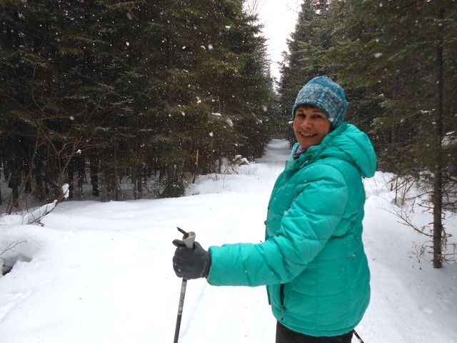 woman cross country skiing with a down coat on