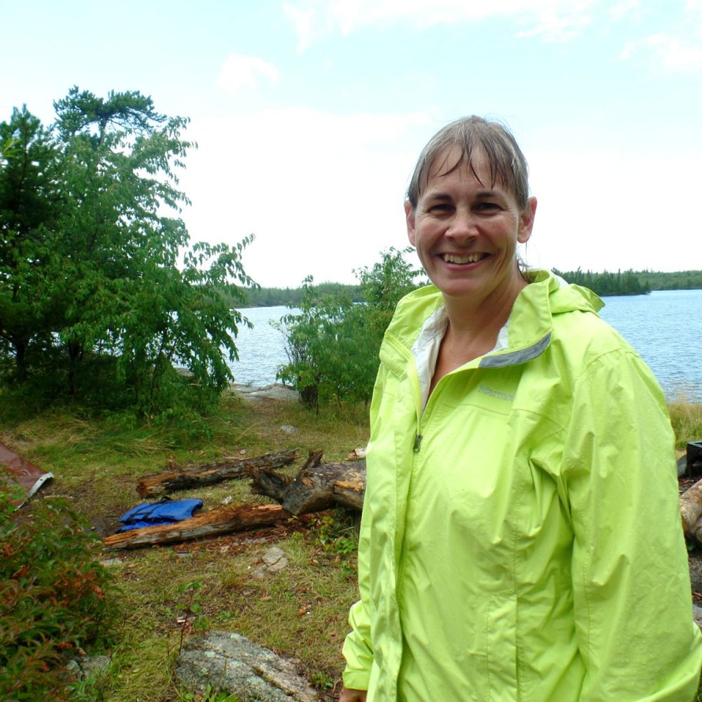 woman wearing a Marmot PreCip jacket on a canoe trip