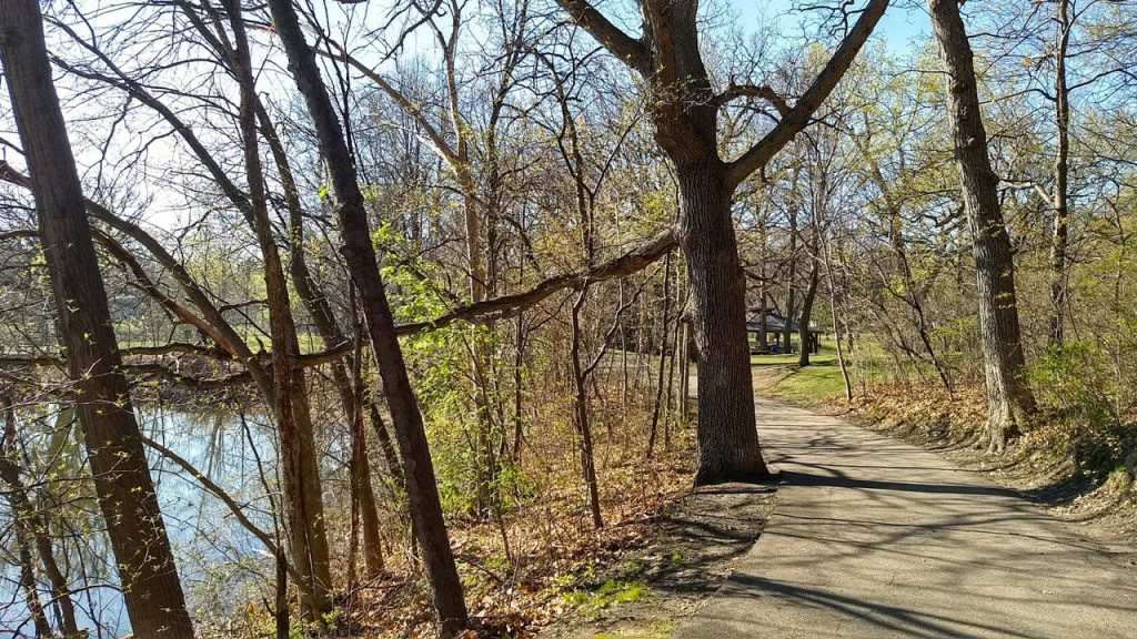 paved hiking trail in kordiak county park, around a lake in mid-spring