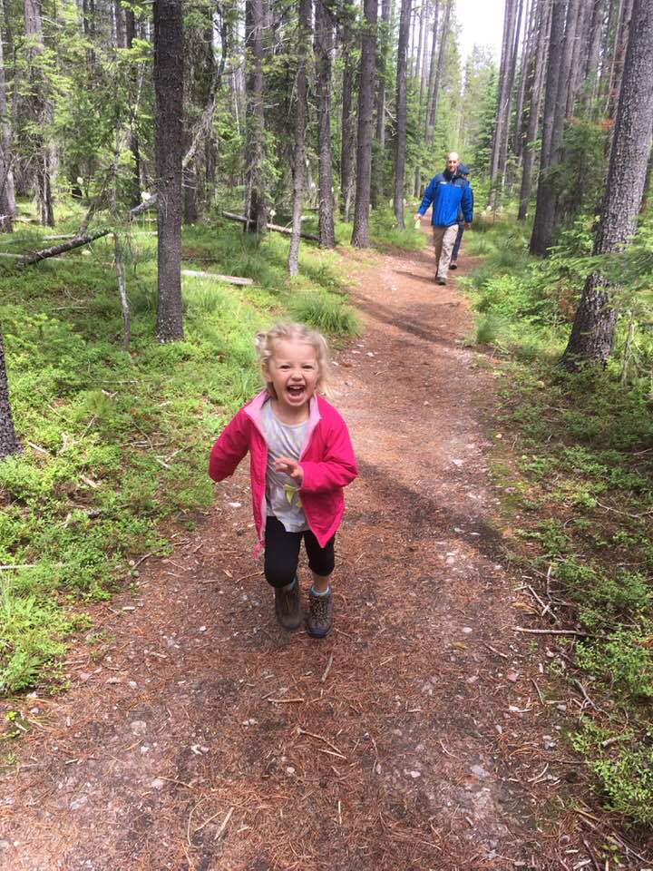 little girl hiking with her dad in the woods