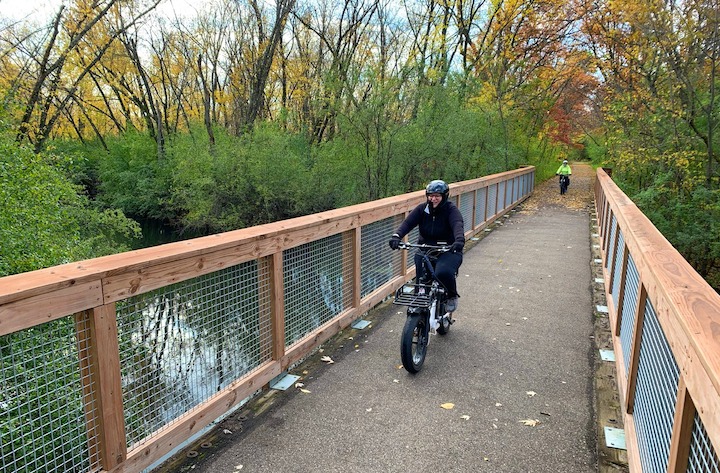 two bikers crossing a bridge on the trail, on electric bikes