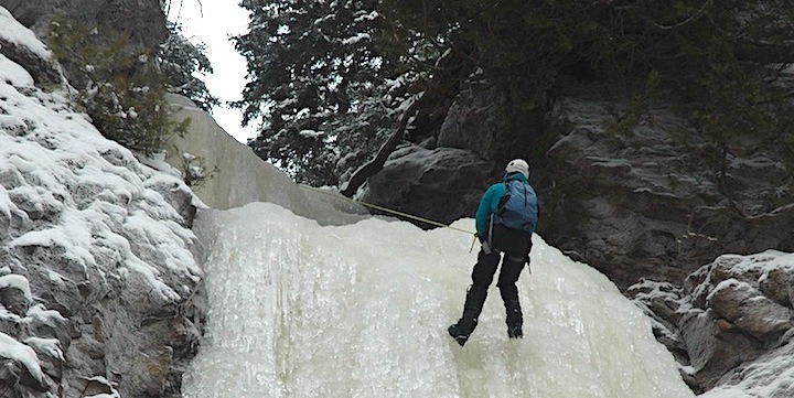 ice climber climbing up a frozen waterfall