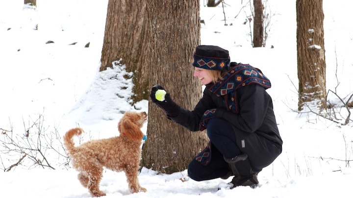 woman playing with her dog in the snow, wearing Polar Mitts gear