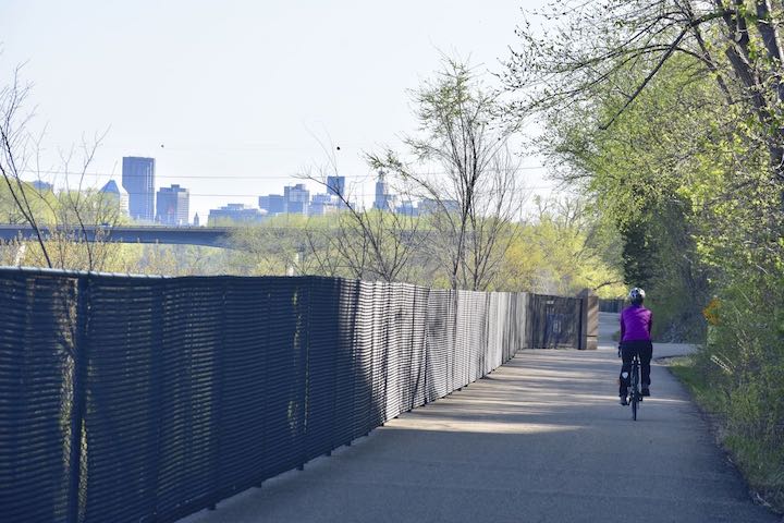 biker on big rivers regional trail with St Paul skyline in the background