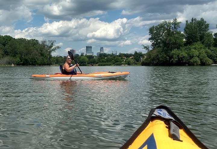 kayakers on lake of the isles with minneapolis skyline behind