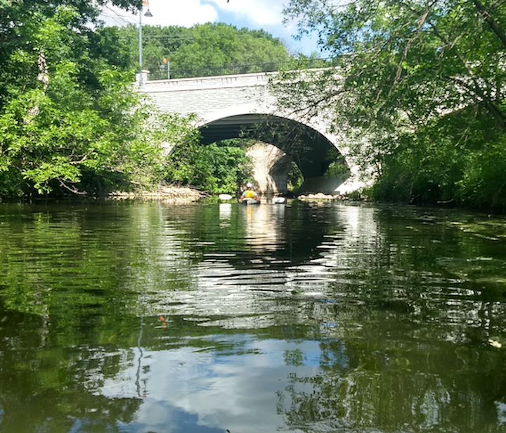 kayaker going under a road bridge on keller creek
