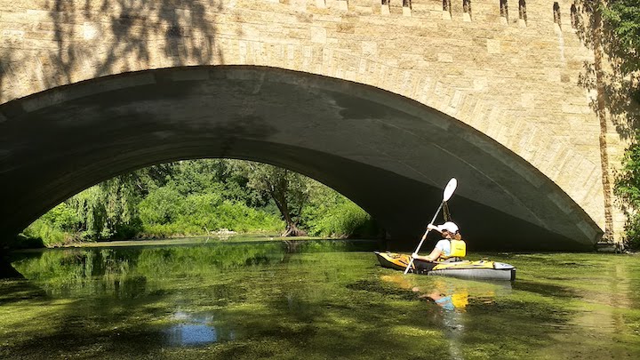 woman kayaking under a bridge on keller creek