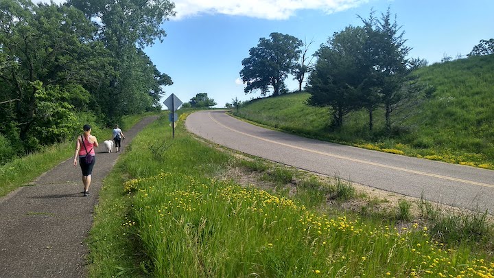 hikers and dog on the paved trail that connects the Deer Loop Trail to the parking area by the main gate