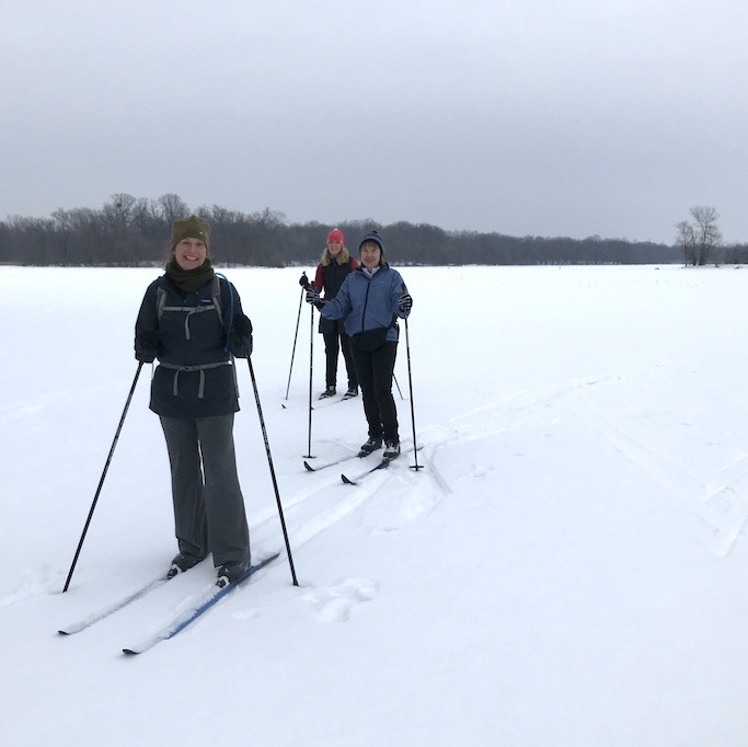 three women on cross country skis on a frozen lake