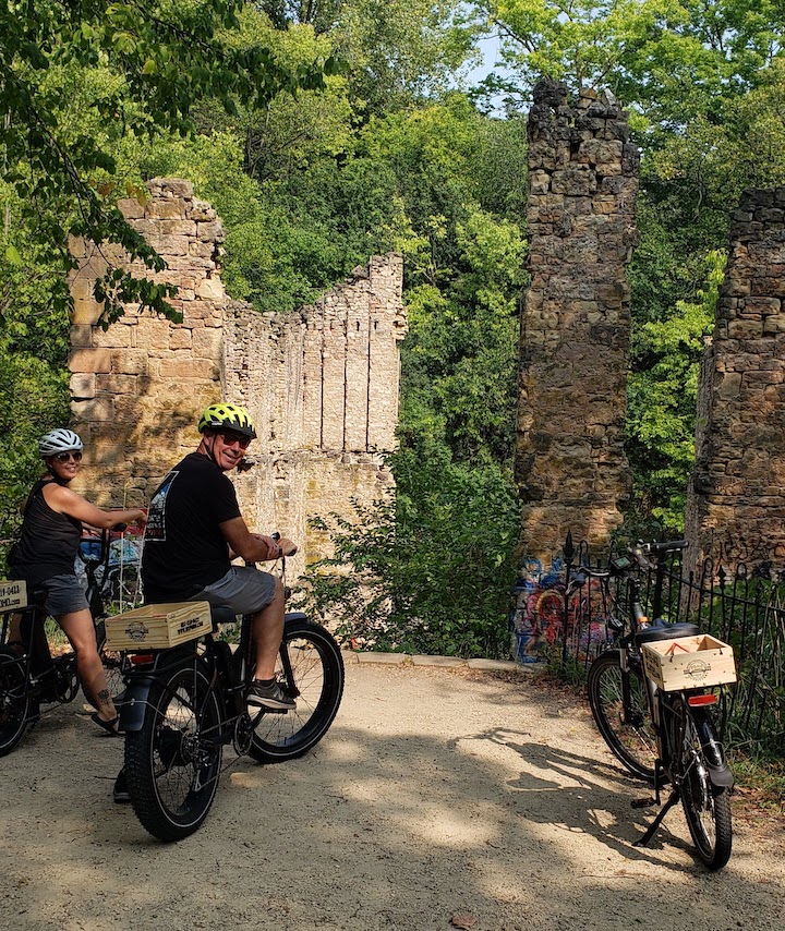 two people with electric bikes on a trail by the Old Mill ruins