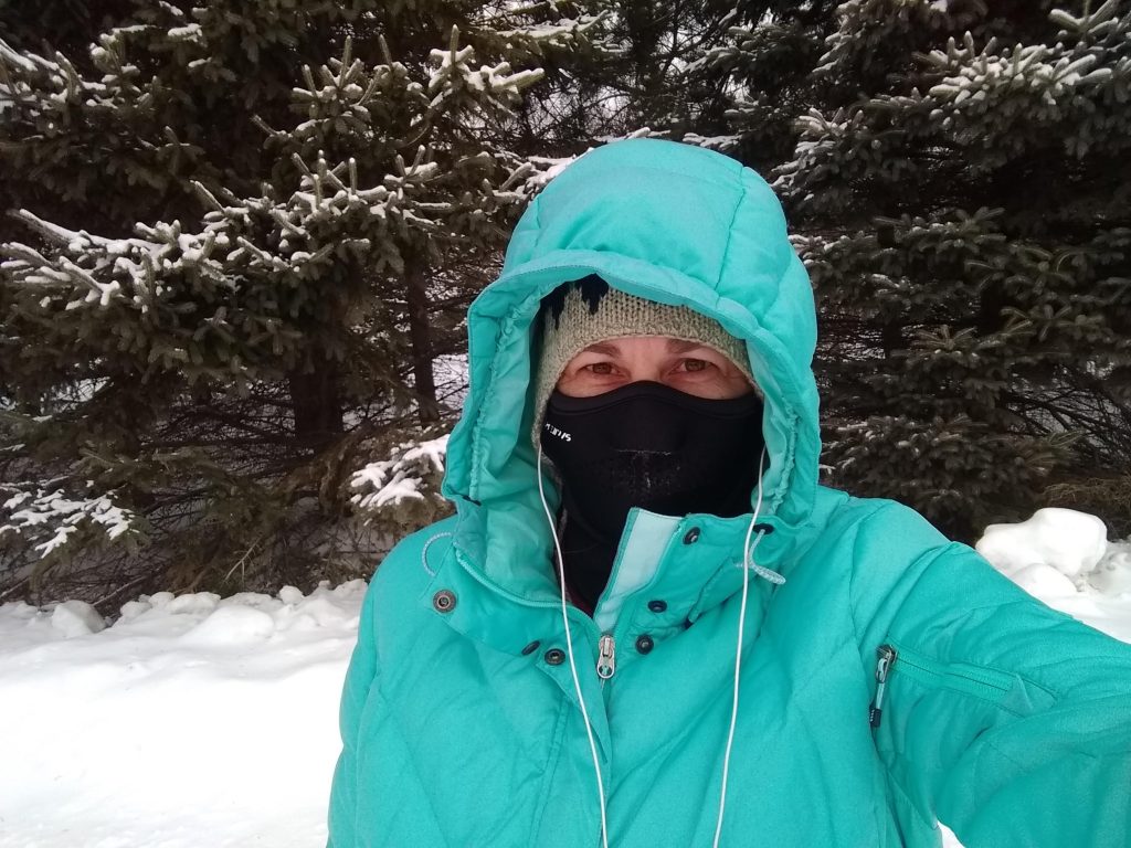 woman wearing a down coat and seirus face mask on a winter day