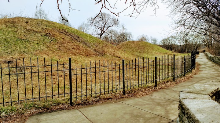 indian mounds behind fence next to trail