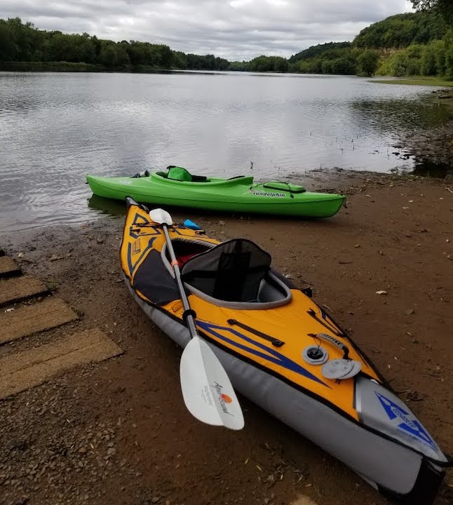 two kayaks on a river bank, kayak paddle laying across one
