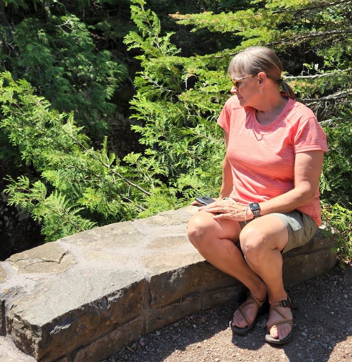 woman wearing Kuhl's Freeflex Cargo Shorts, sitting on a stone wall