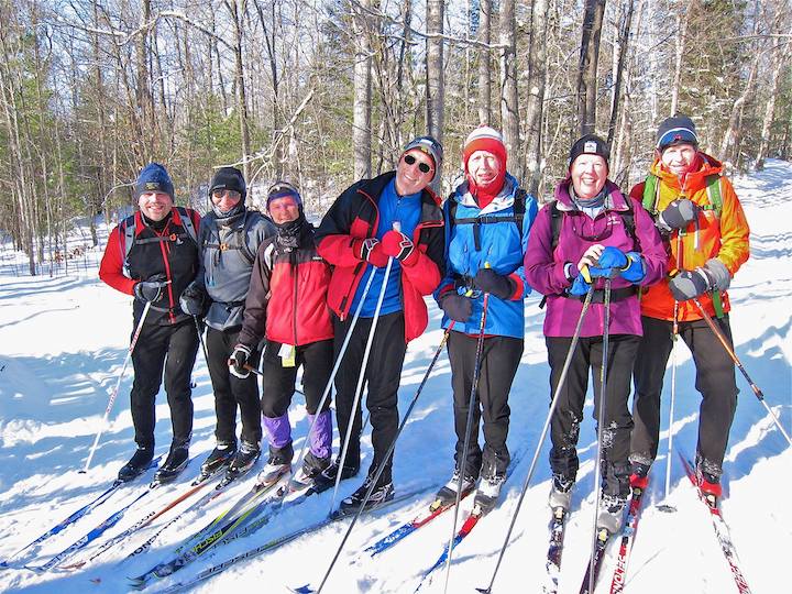 group of adult men and women cross country skiing together