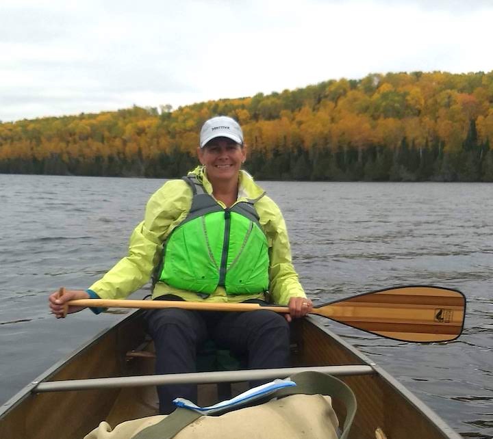 woman in canoe with Marmot precip jacket, in the fall