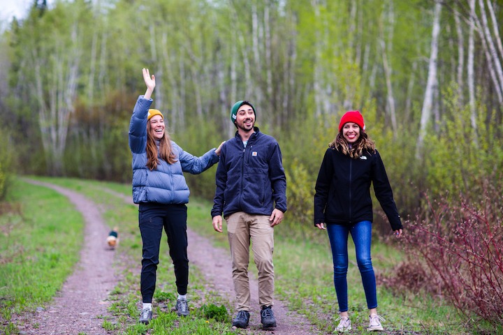 three young adults hiking in the woods, each wearing a different colored FLORT beanie