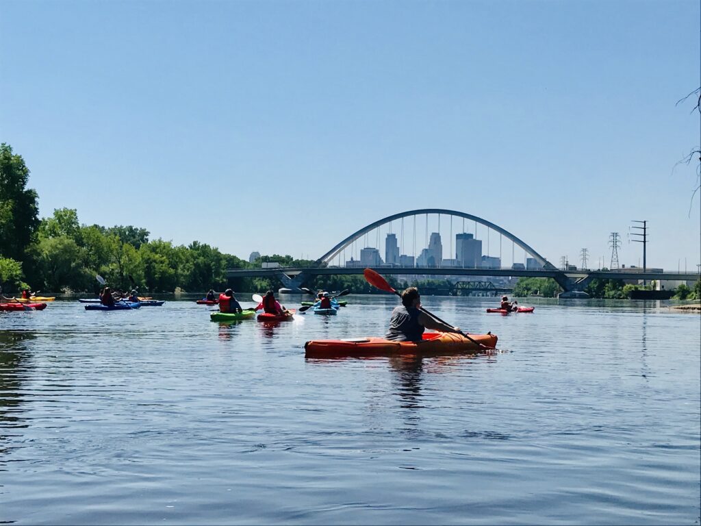 kayakers on the Mississippi River with Minneapolis skyline in the distance