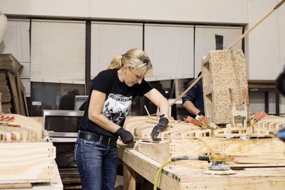 a woman works on building her own wood paddleboard at a Shore Boards workshop