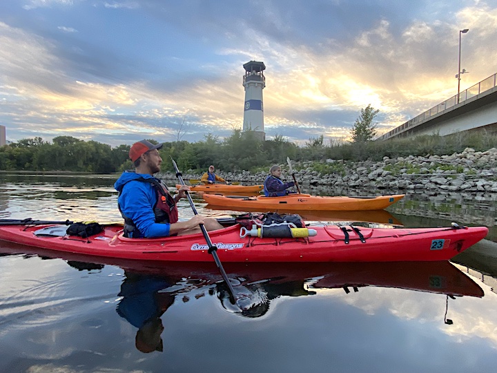 three kayakers on a river at sunset