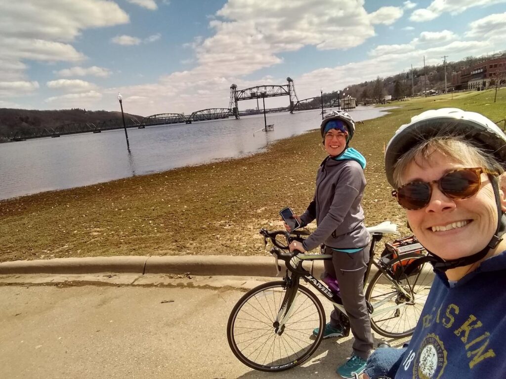 two women at st. croix river, historic bridge in background; st croix river crossing loop trail