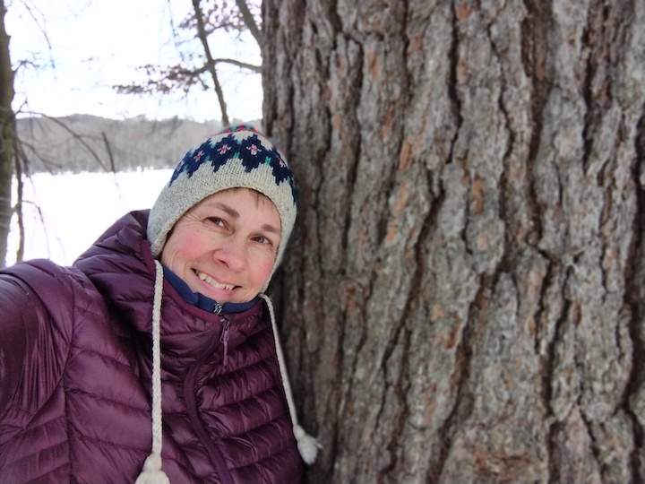 woman next to a large white pine tree in the winter