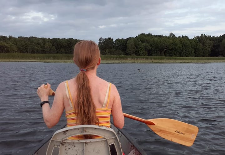 Regan pauses canoeing to look at a loon in the water ahead
