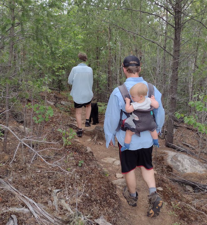 a family hikes on a rocky, wooded trail