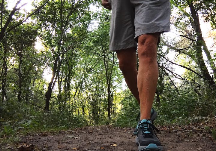 a woman's legs and feet hiking on a dirt trail