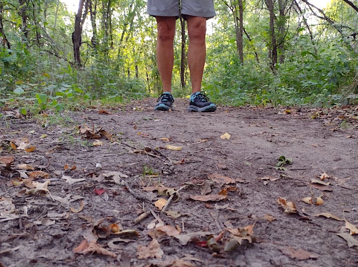 woman's legs and feet on a dirt hiking trail in the woods