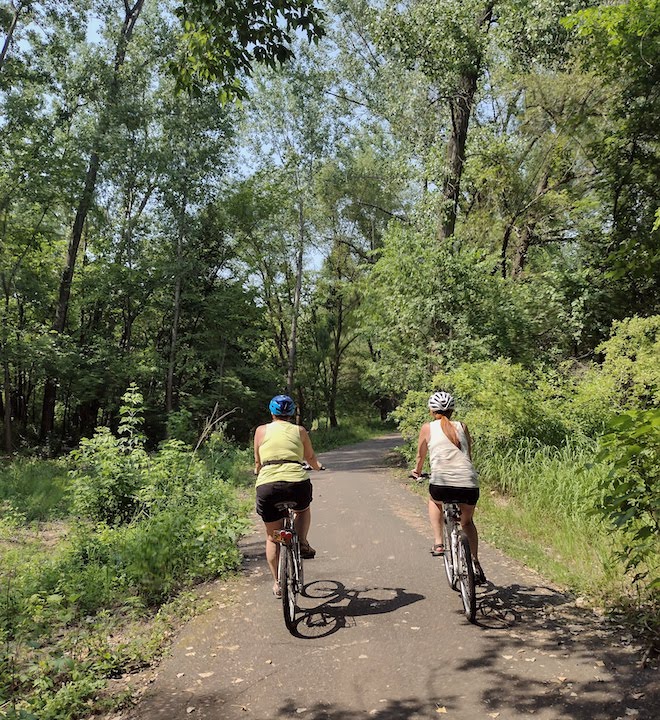 two women bike a wooded trail