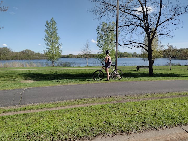 biker stops to enjoy the day next to a lake, early spring
